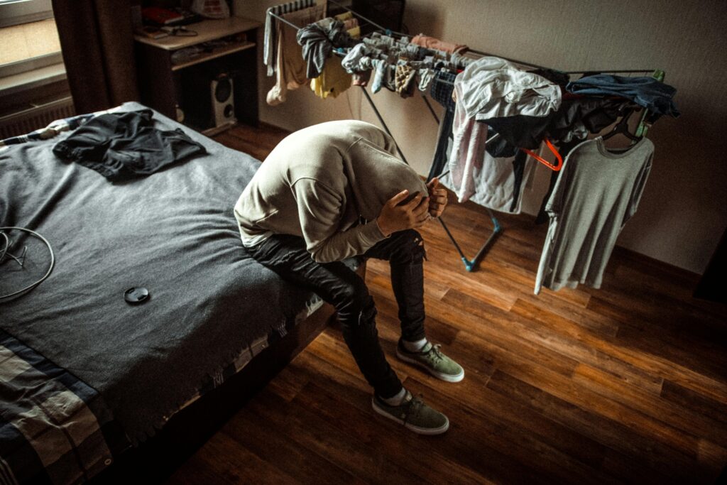 A person sits on a bed in distress, emphasizing mental health awareness.